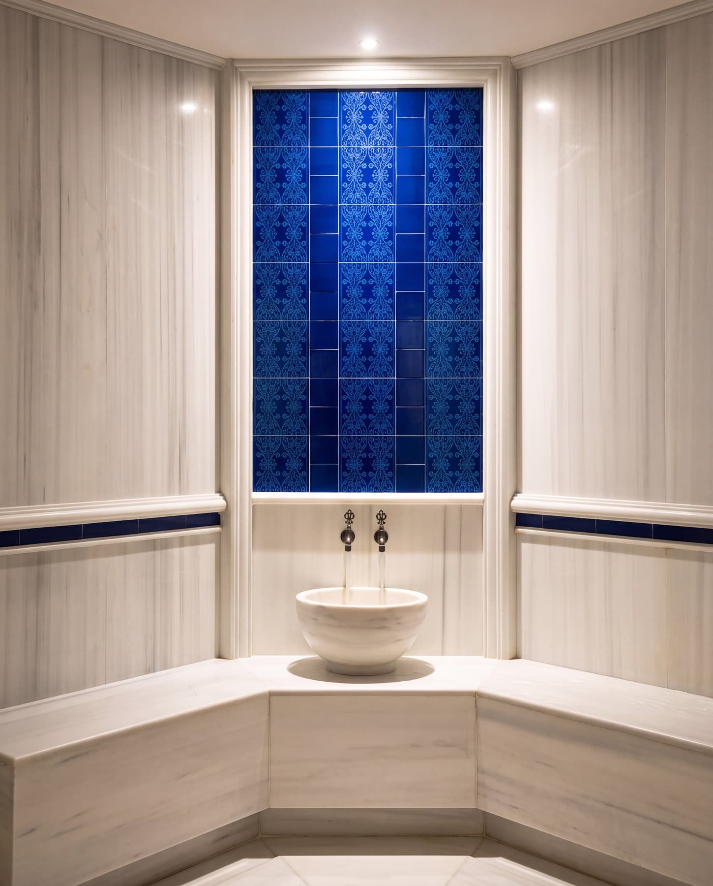Navitas Spa hamamı — mavi çinili duvar, beyaz mermer sekiler ve kurna